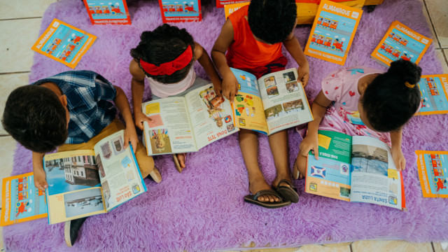 Crianças lendo almanaque do projeto Trilhos da Alfabetização